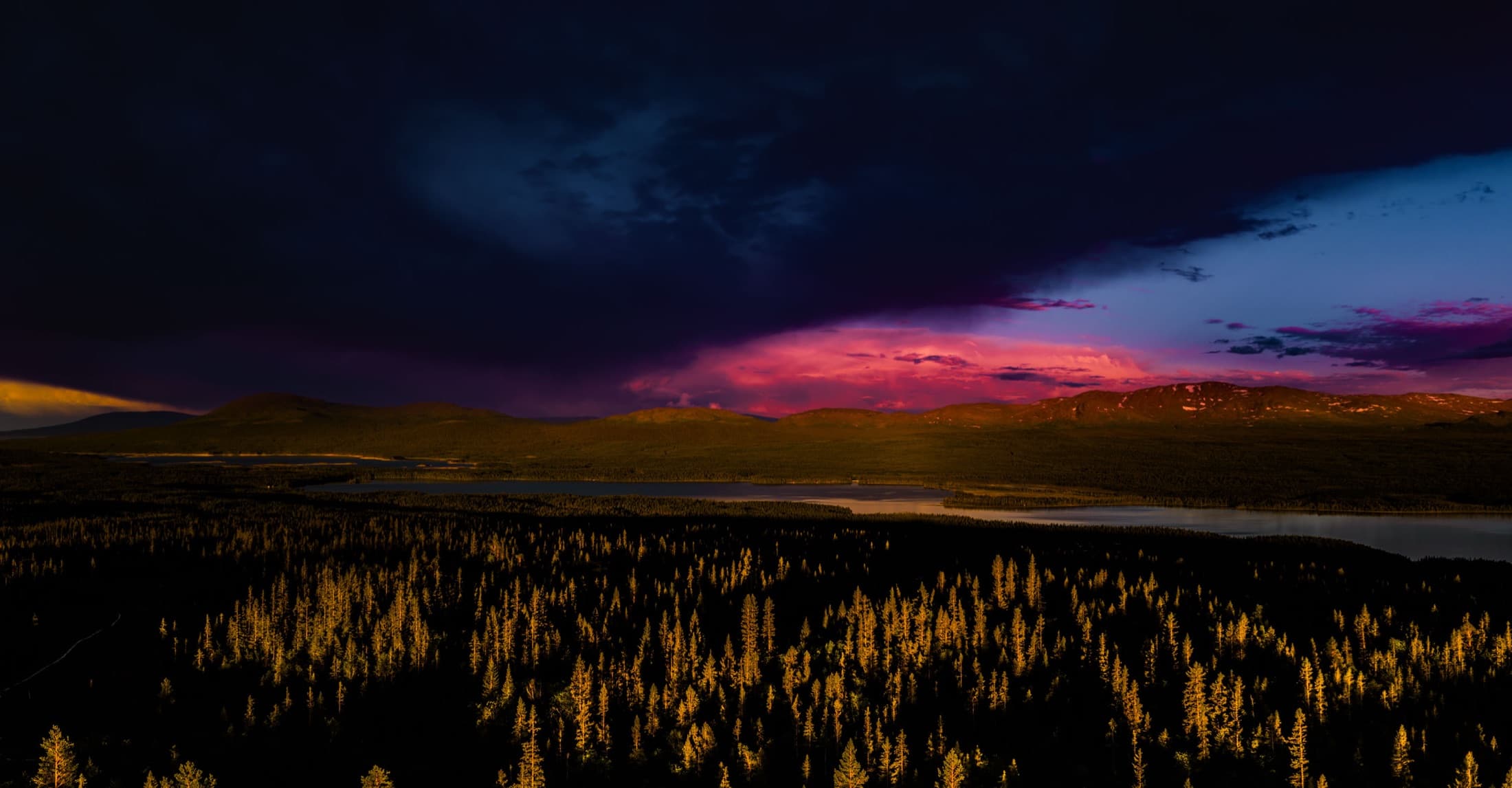 The sunset that made the trip — storm light breaking over the forest and lake.